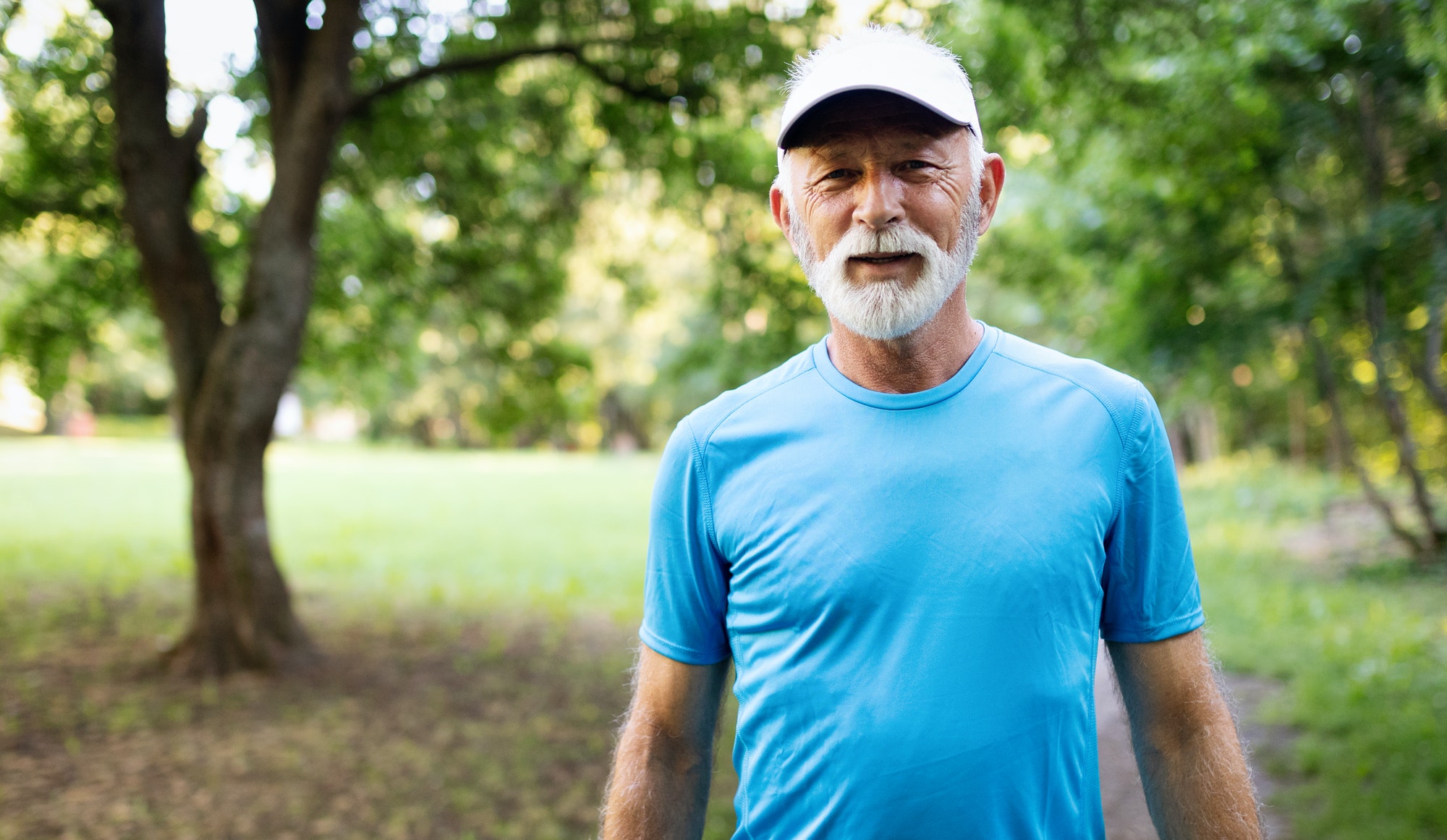 Attractive retired man with a nice smile jogging in park