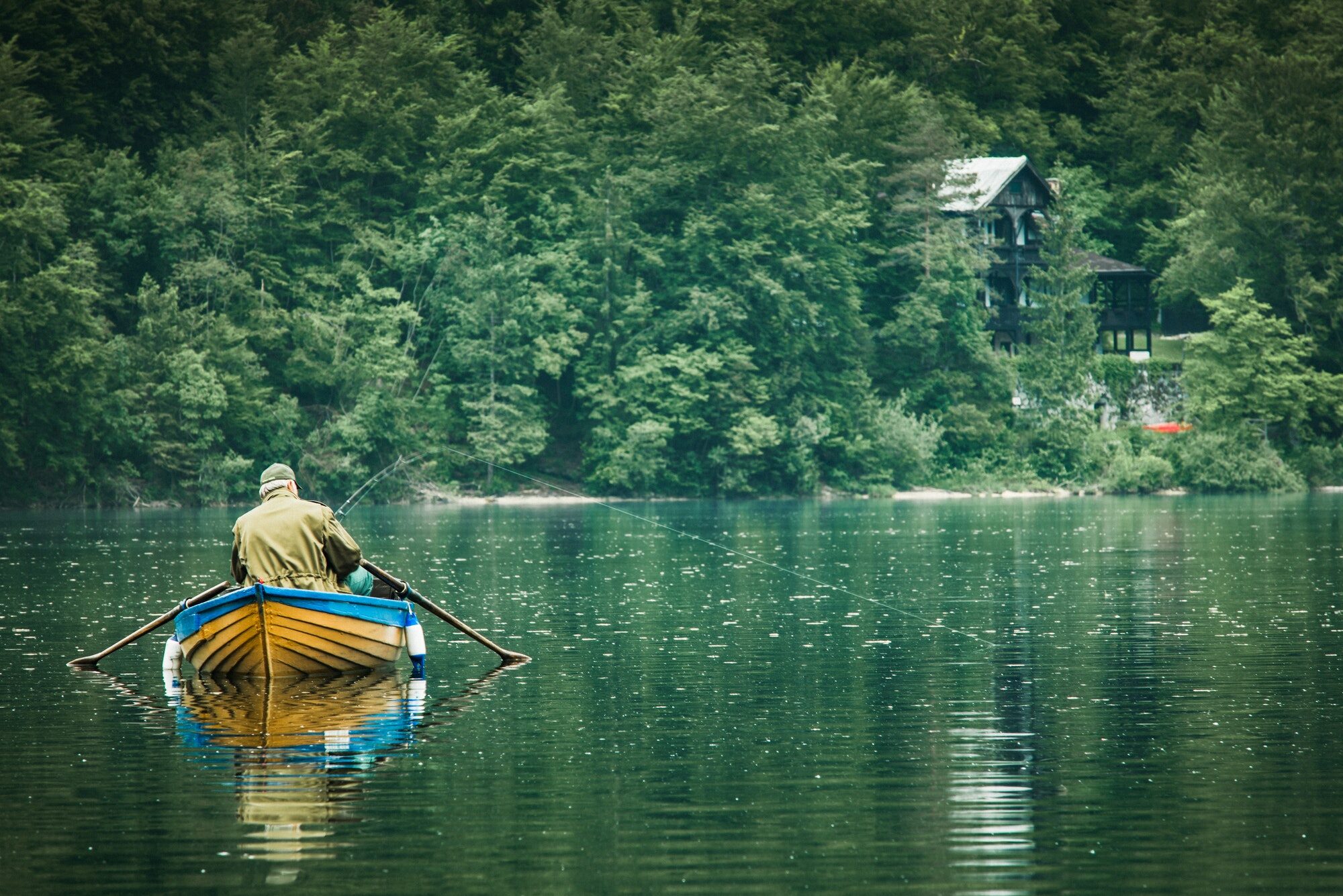 retired old man fishing from boat at lake