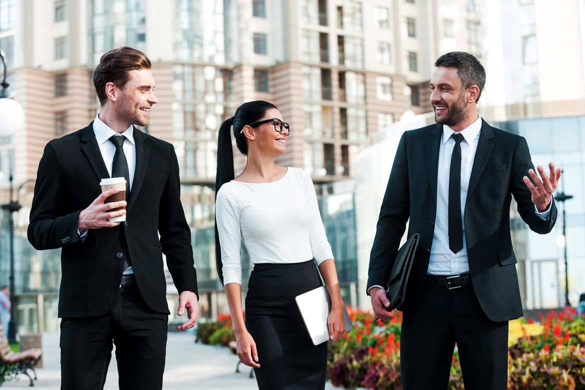 Three people in business clothing discussing an event sponsorship package.